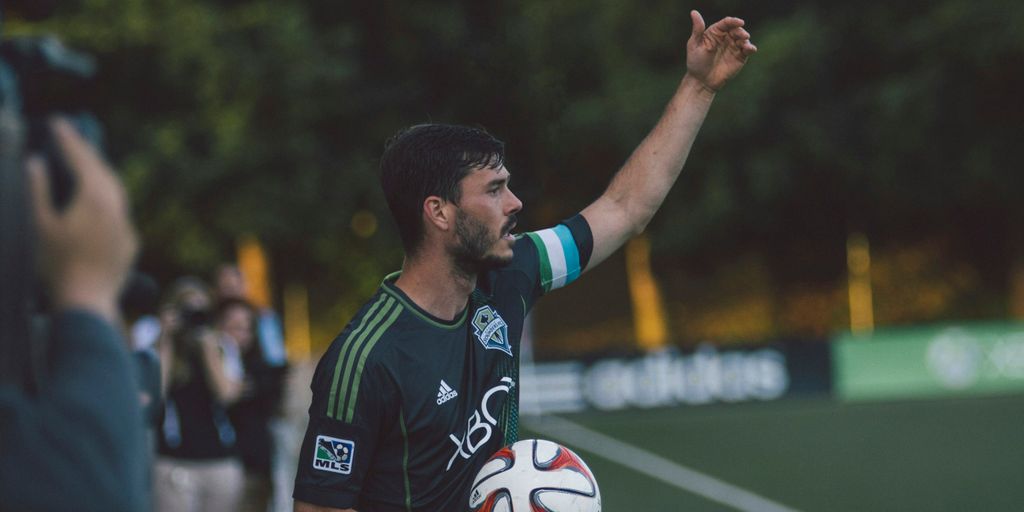 man in black and green Adidas jersey shirt holding soccer ball