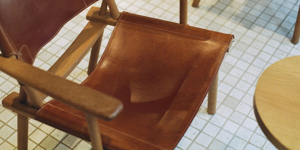 a brown leather chair sitting on top of a tiled floor