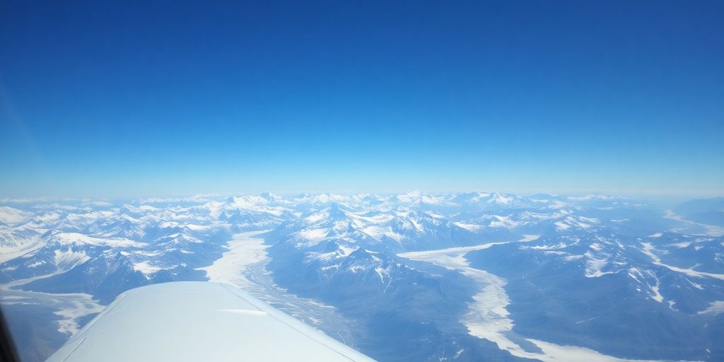 A small tour airplane flying over snow-covered Alaskan mountains.