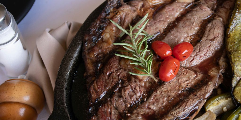 grilled meat with tomato and green vegetable on black pan