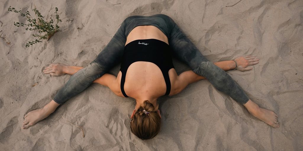 a woman laying on the sand with her back to the camera