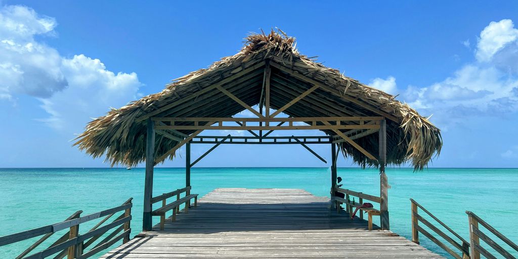 a wooden pier with a thatched roof over the ocean