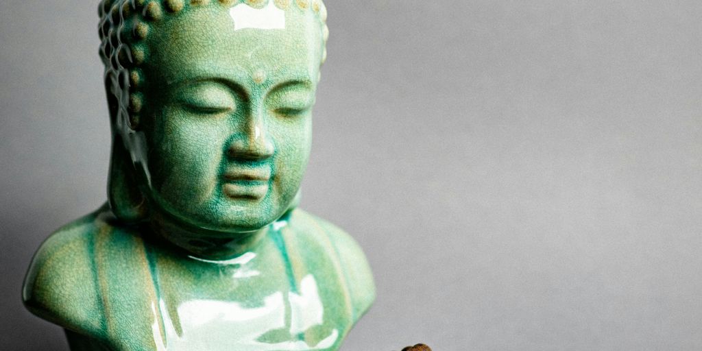 A buddha statue next to a beaded bracelet