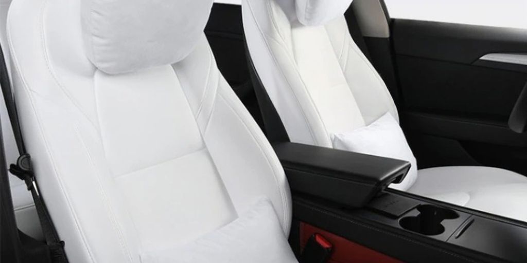 Two white car seats with neck pillows and armrest.