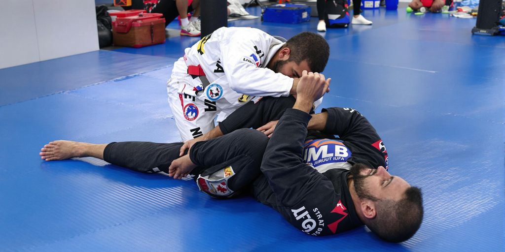 BJJ practitioners rolling on a mat during training.