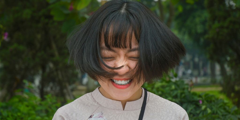 woman smiling closing eyes while flipping her hair