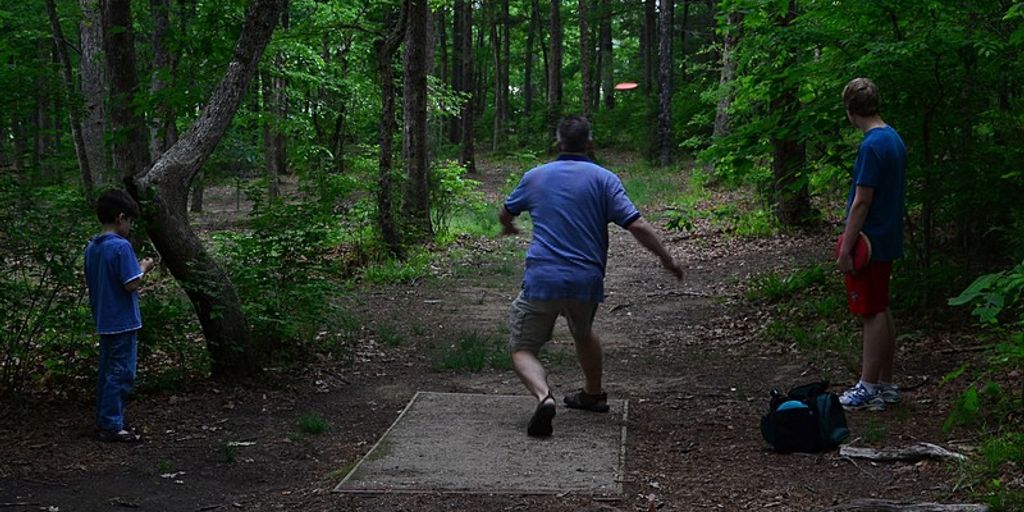 family playing disc golf in a park near Huntsville
