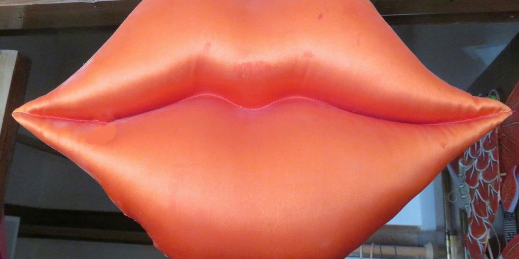 a large orange lip shaped balloon hanging from a ceiling