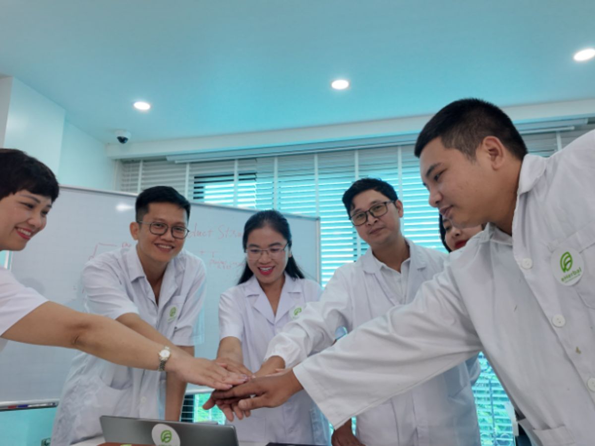 A team in lab coats is collaborating and celebrating together.