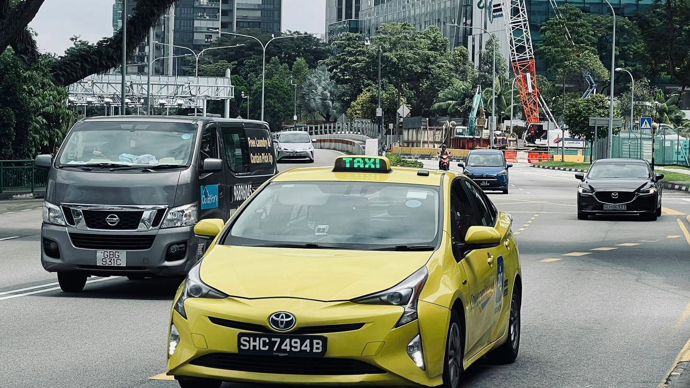 a yellow taxi cab driving down a street next to tall buildings