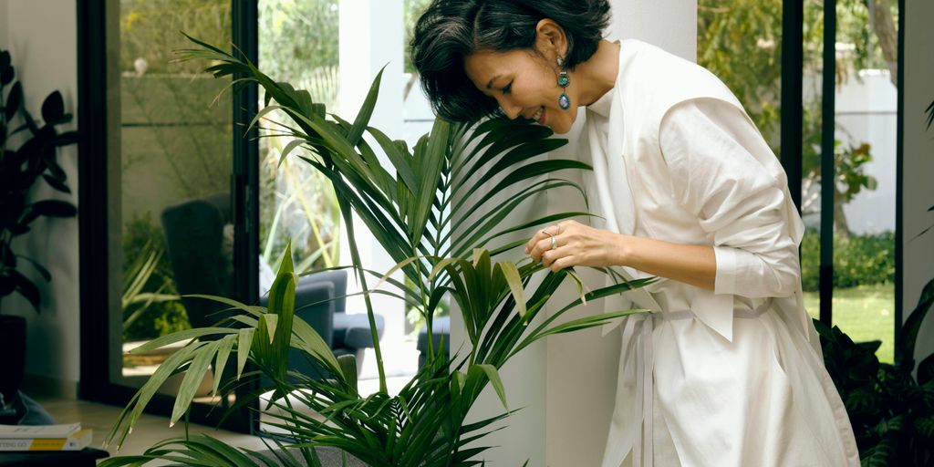 woman in white robe holding green plant