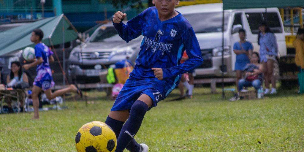 a young boy kicking a soccer ball on a field
