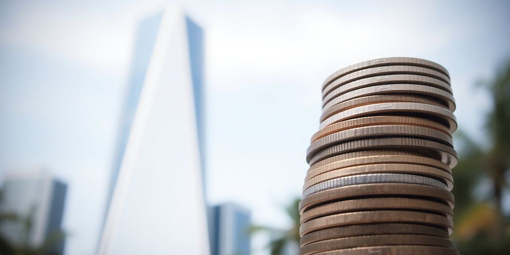 Monedas en crecimiento con edificio moderno al fondo.