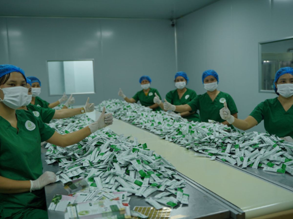 People in green uniforms working with packaged products on a table.
