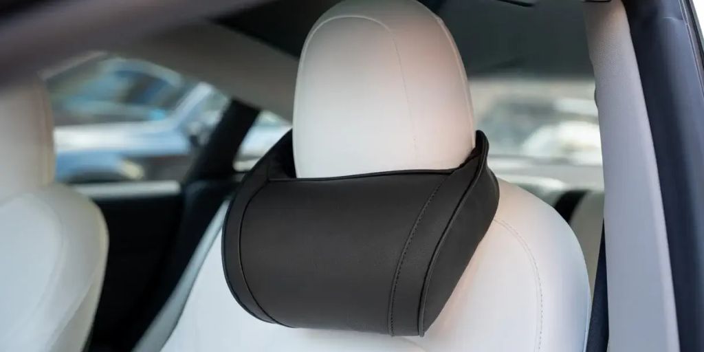 Car seat with a black headrest cushion attached.
