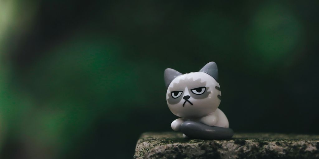 white cat figurine on brown rock