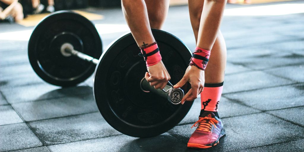 person locking gym plates on barbell