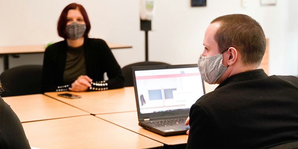 a group of people sitting around a table wearing face masks