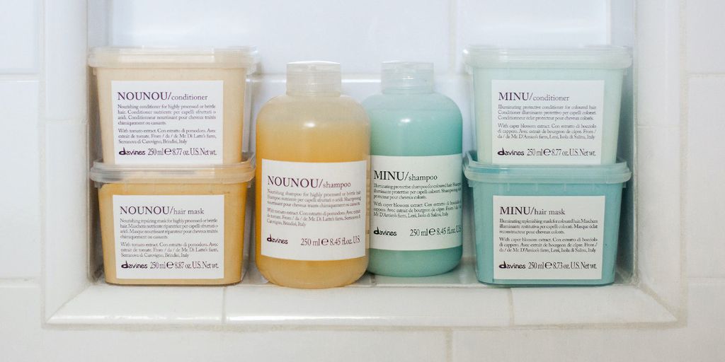 Four bottles of haircare products on a shower ledge.