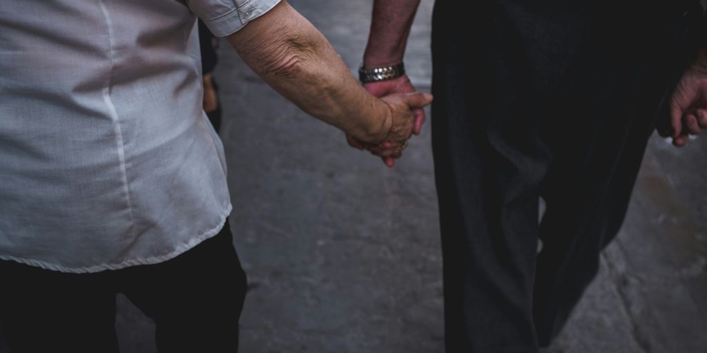 man and woman holding hands while walking during daytime