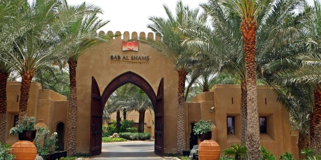 the entrance to a resort surrounded by palm trees