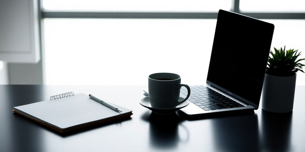 Modern workspace with laptop, notepad, and coffee cup.