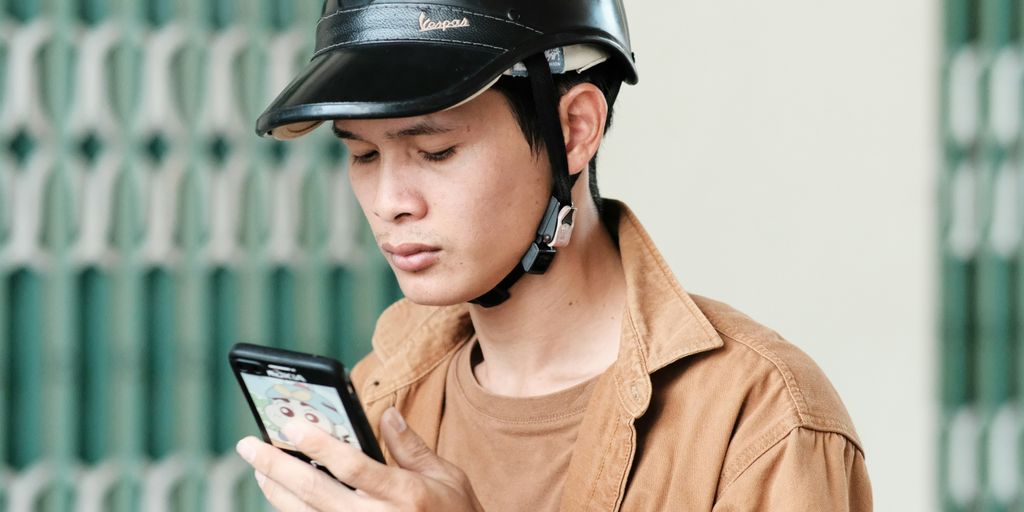 a man wearing a helmet looking at a cell phone