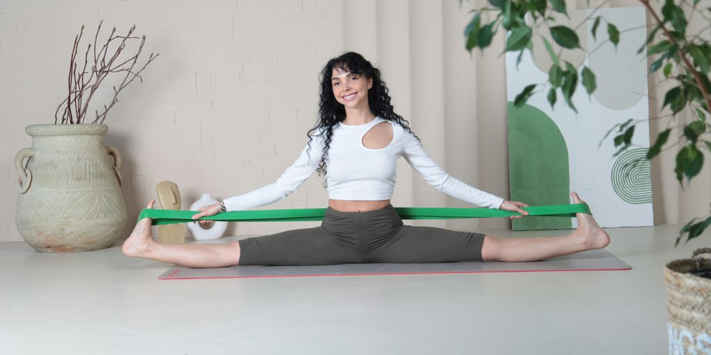 a woman sitting on a yoga mat holding a green ribbon