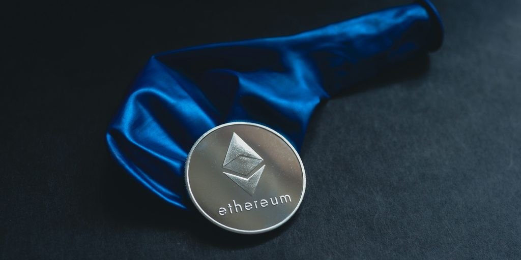Ethereum medal resting on a blue satin fabric backdrop.