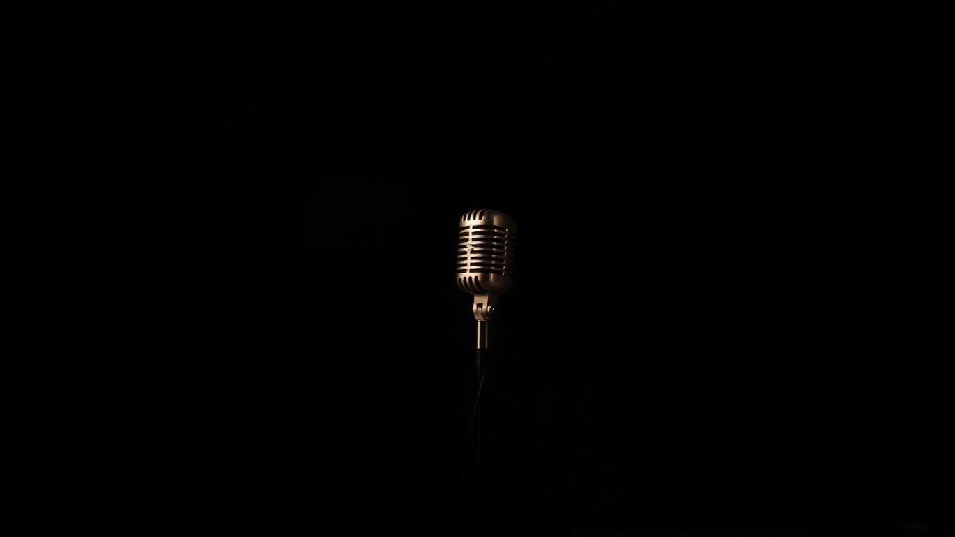 Spotlit vintage microphone on a dark stage.
