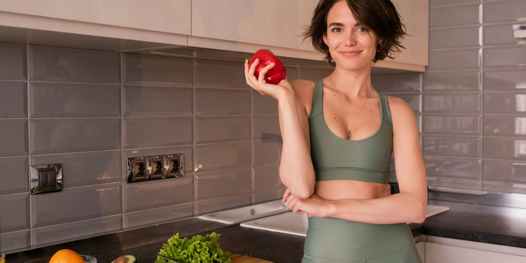 a woman standing in a kitchen holding an apple