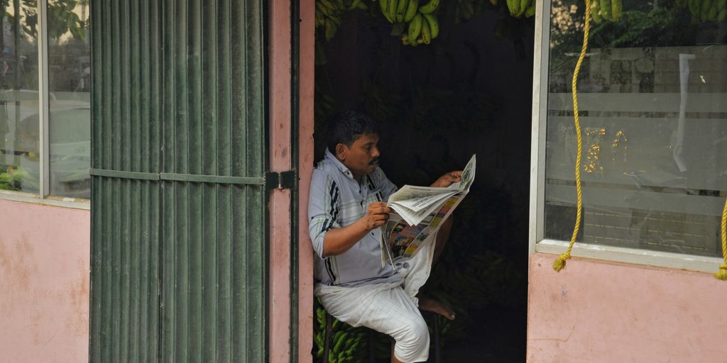 man in white button up shirt and white pants sitting on brown wooden chair