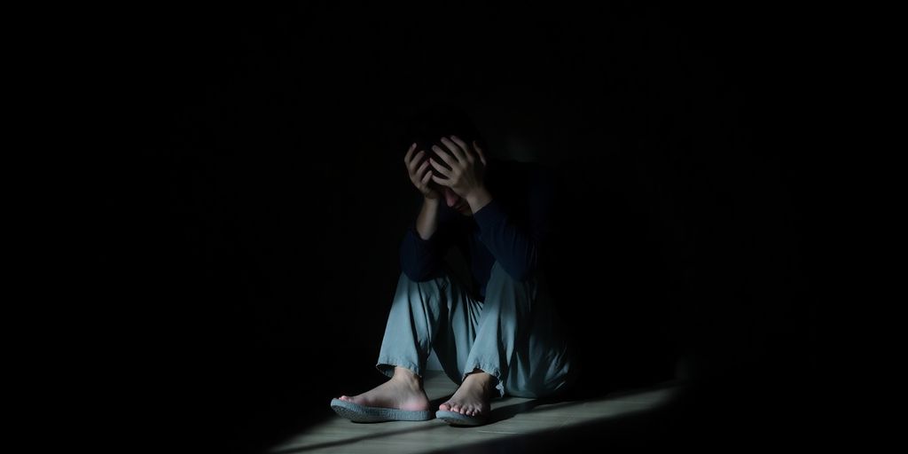 Person sits alone, head in hands.