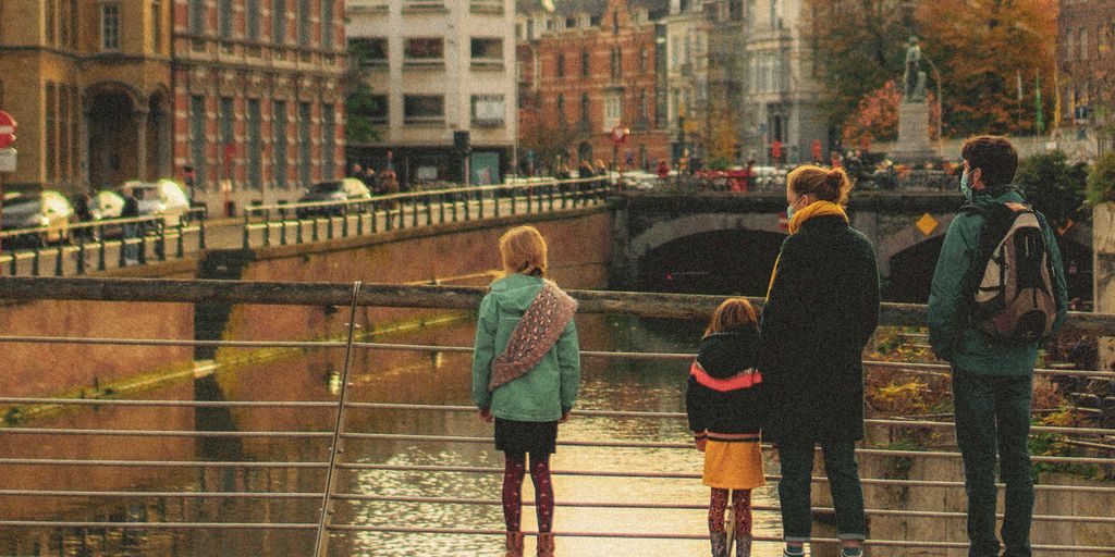 man in black jacket and blue denim jeans walking on bridge during daytime