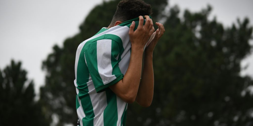 a soccer player covers his face with his hands