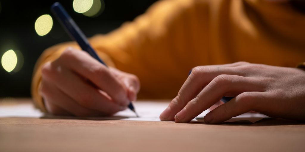 A person writing on a piece of paper with a pen