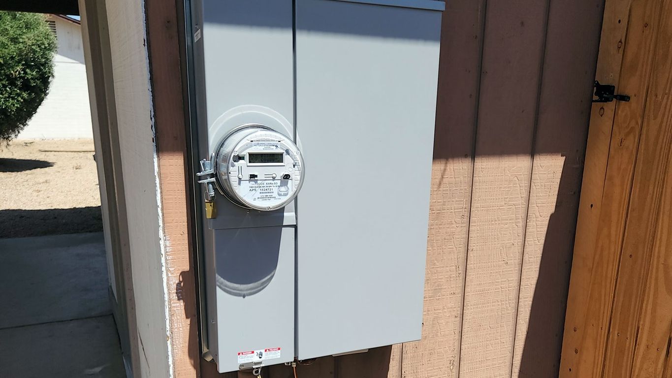 Electric meter mounted on a wall beside a door.