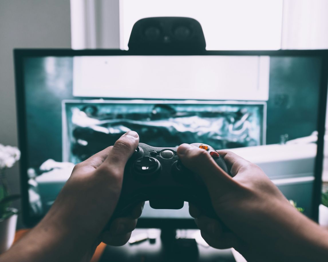 person holding game controller in-front of television