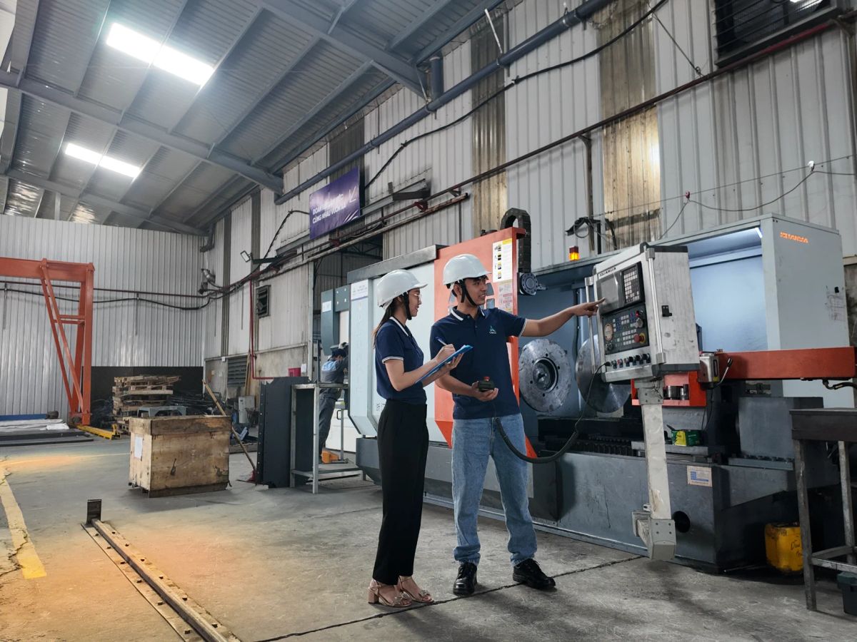 Two individuals discussing machinery in an industrial workshop setting.