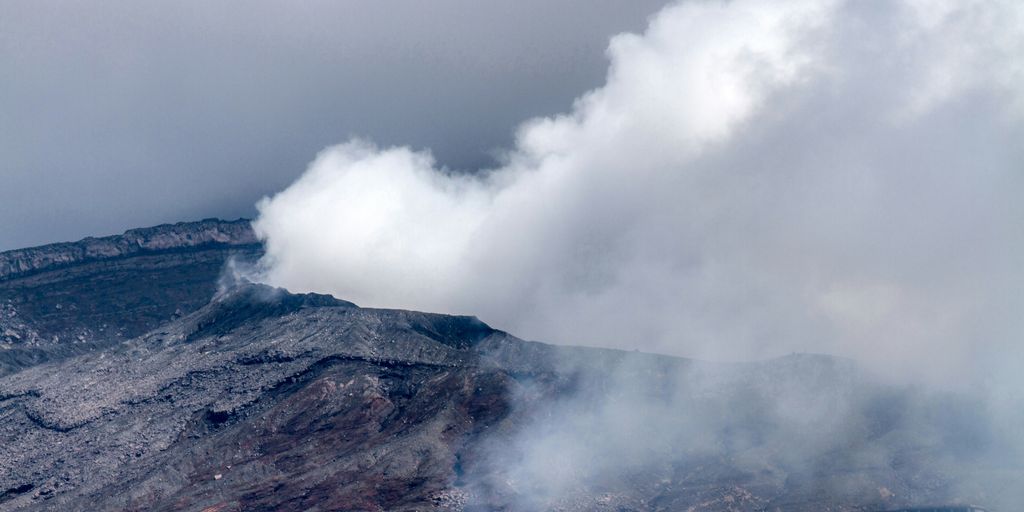 smoke billows from the top of a mountain