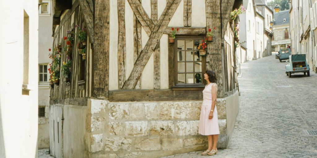 a woman in a pink dress standing in front of a building