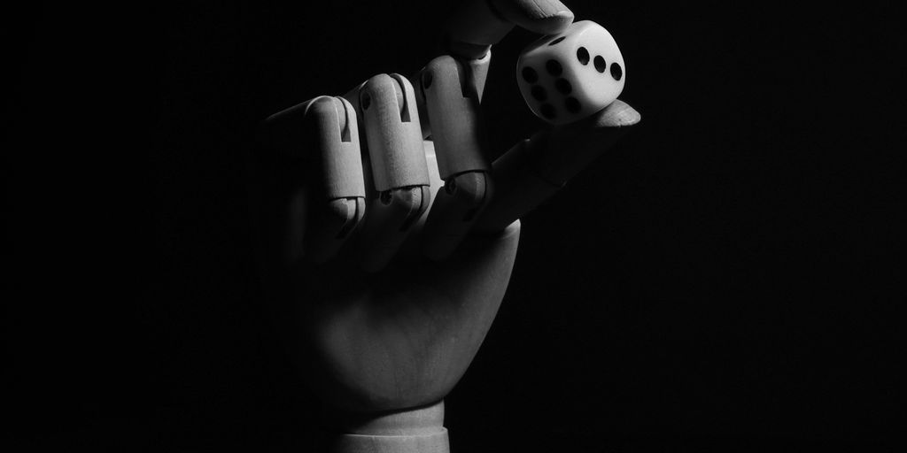 A black and white photo of a hand holding a dice