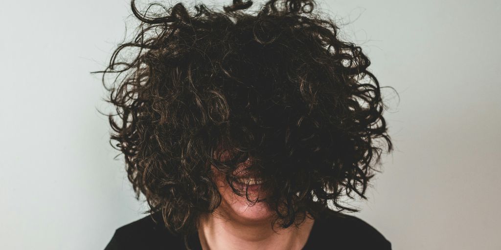 person with curly hair covering face