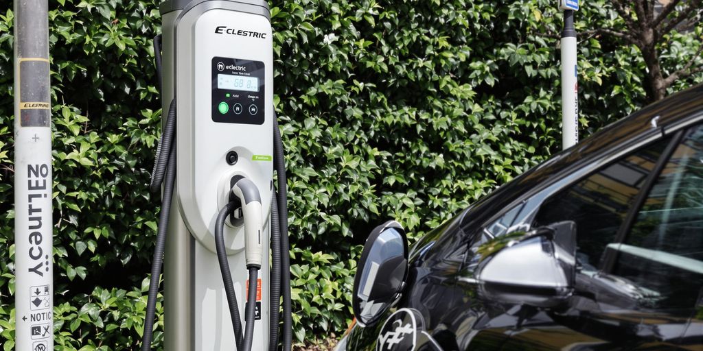 Electric vehicle charging station with parked car and greenery.