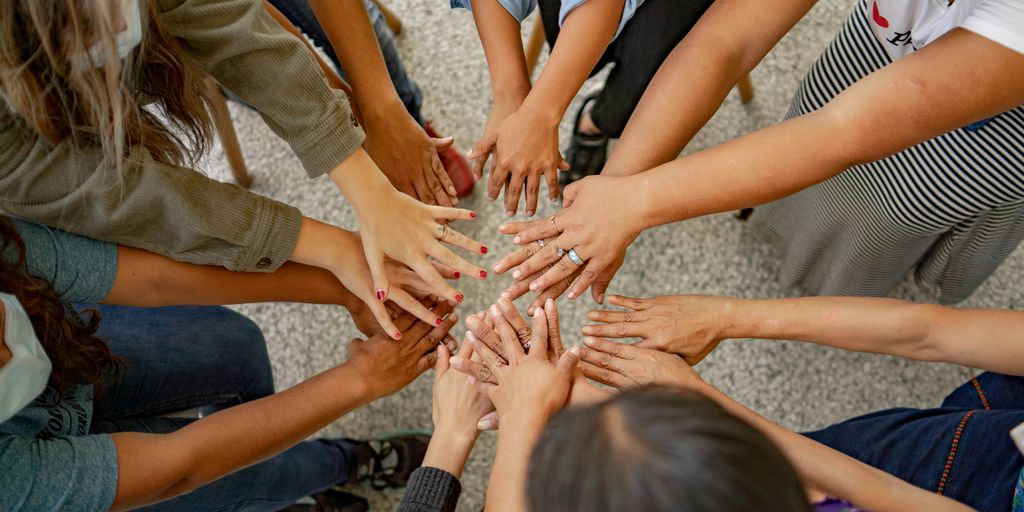 A group of people standing in a circle with their hands together