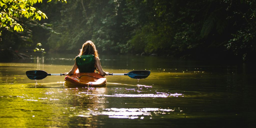 woman on kayak on body of water holding paddle