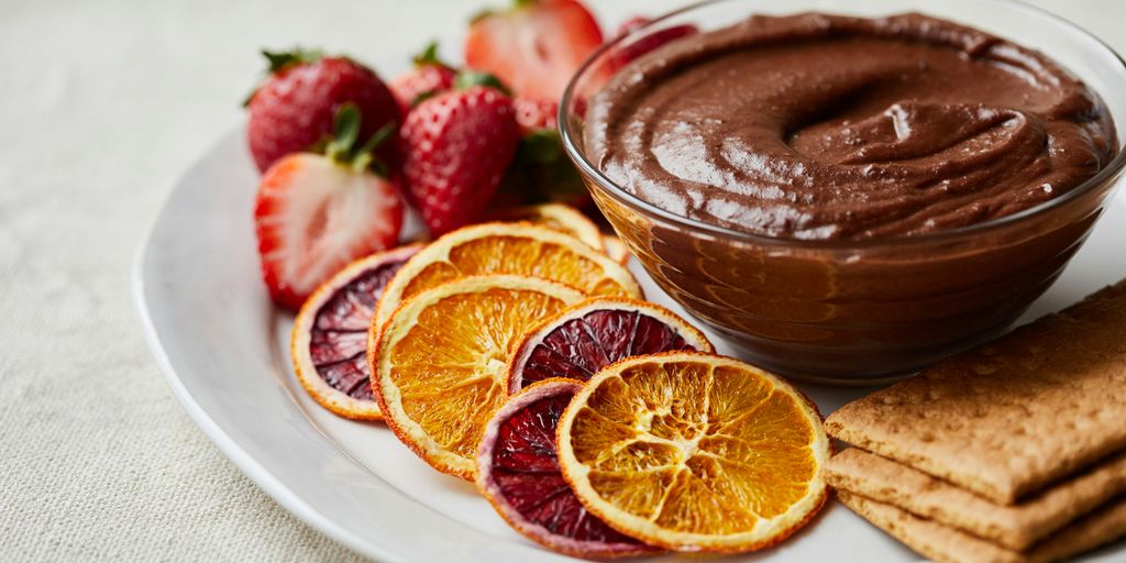 a white plate topped with fruit and a chocolate dip