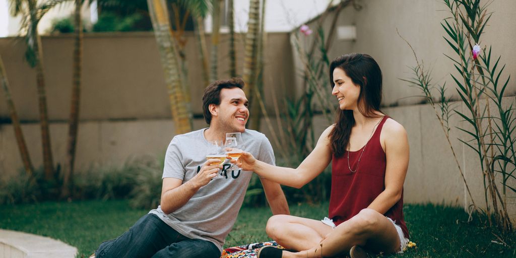 a man and a woman sitting on a blanket on the grass