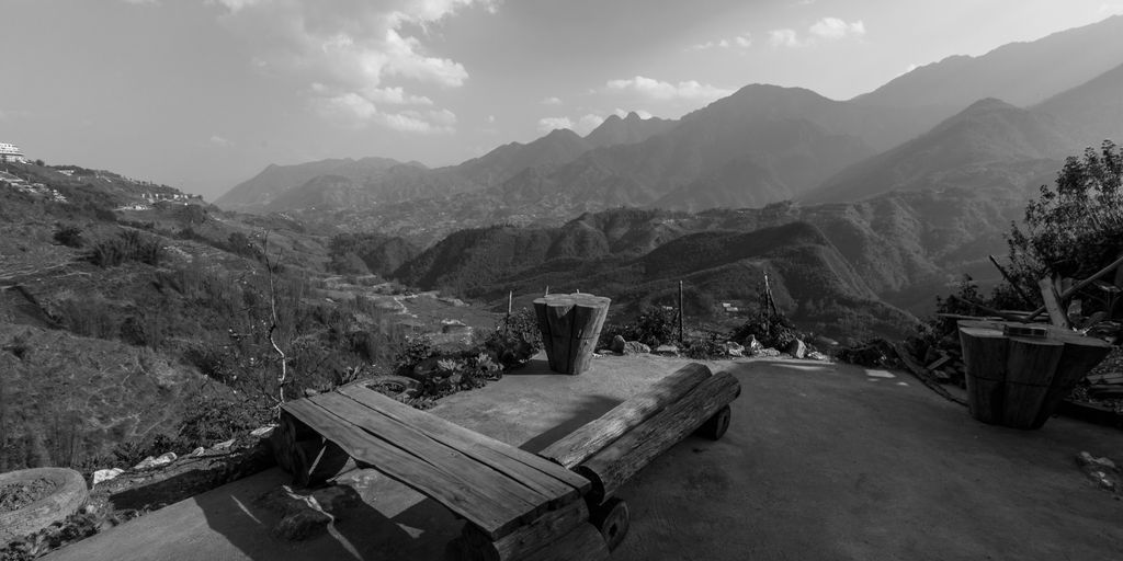 a black and white photo of a bench and mountains