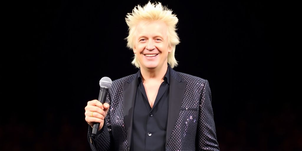 Rod Stewart smiling, wearing a sparkly jacket, holding a microphone.